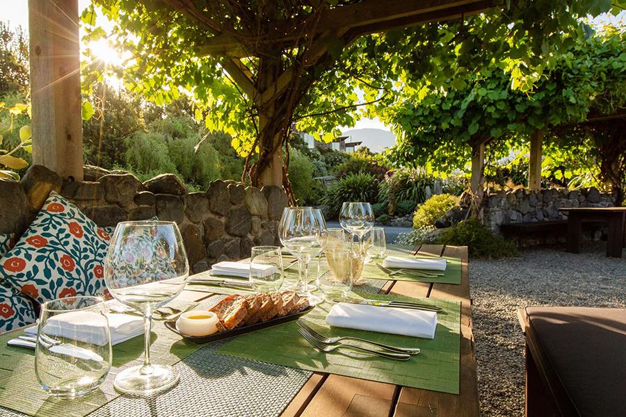 Dine outdoors with sunlight filtering through the trees at Hapuku Lodge | Photo credit: Hapuku Lodge
