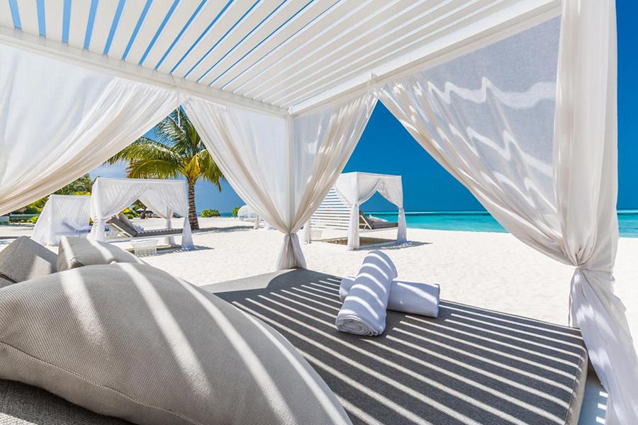 Unwind on a luxury beachfront day bed at LUX South Ari Atol | Photo credit: LUX